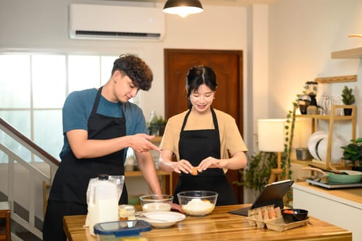 Happy couple preparing ingredients for pancakes in a kitchen.