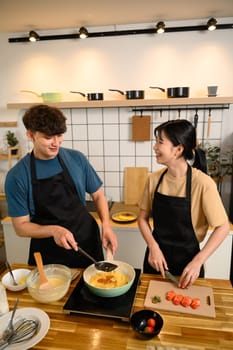Smiling couple cooking breakfast together in the kitchen.