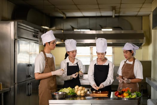 Cooking instructor guiding students in vegetable preparation during hands on class.