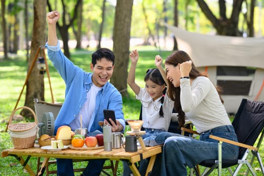 Happy parents and daughter enjoy outdoors during a camping in nature.
