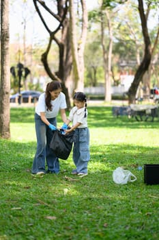 Mother and daughter collecting garbage together in a park.
