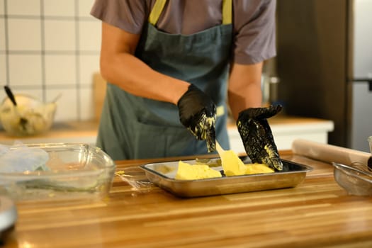 Close up of man shaping fresh homemade butter in a metal tray.