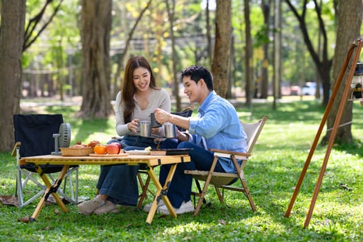 Smiling couple enjoying coffee together at a peaceful campsite surrounded by nature.