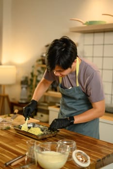 Young man making homemade compound butter on a wooden kitchen counter.