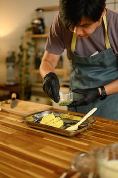 Man sprinkles fresh herbs into softened butter, preparing homemade compound butter..