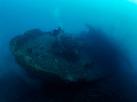 unrecognizable scuba diver diving on a sunken ship in the blue ocean, concept of underwater adventure and active leisure lifestyle, copyspace for text
