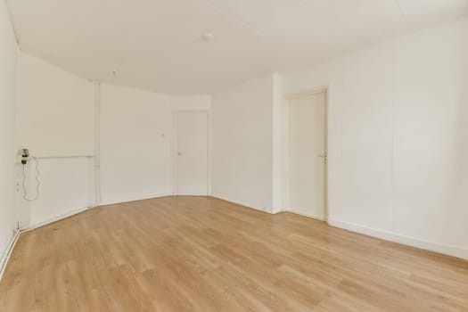 An empty, well-lit interior room showcasing light wooden flooring and plain white walls, offering a clean and minimalist aesthetic.