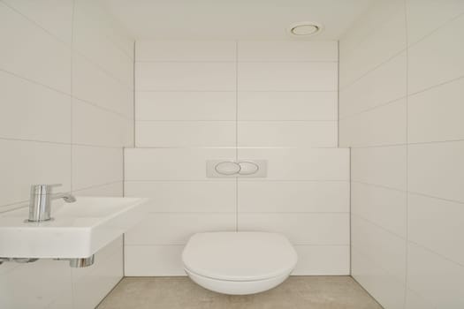 This image showcases a sleek, minimalist bathroom featuring a white toilet and sink against a clean, tiled wall. The design emphasizes simplicity and purity.