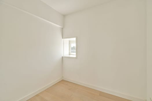 A bright and airy room featuring a small window that allows natural light to flood in, highlighting the simplicity of the space and its clean lines.