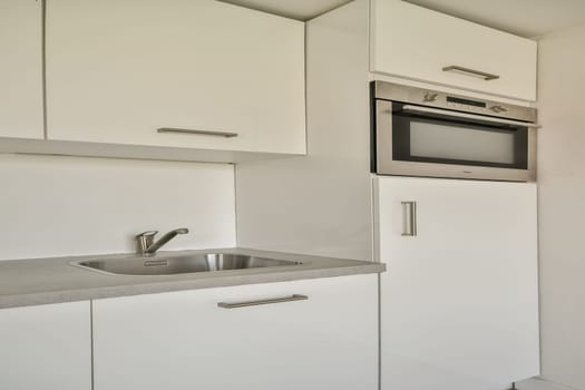 A sleek and contemporary kitchen featuring white cabinetry, stainless steel appliances, and a clean countertop. Ideal for modern living spaces.