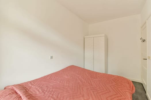 A tranquil minimalist bedroom featuring a neatly made bed with soft, textured textiles, a wardrobe, and subtle wall colors. Ideal for relaxation and simplicity.