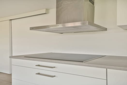 A minimalist kitchen featuring a sleek countertop, a stylish range hood, and clean lines, ideal for contemporary living.