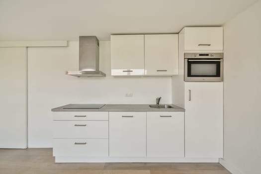 A sleek, modern kitchen featuring white cabinetry, a stainless steel range hood, and integrated appliances. The design emphasizes simplicity and functionality.