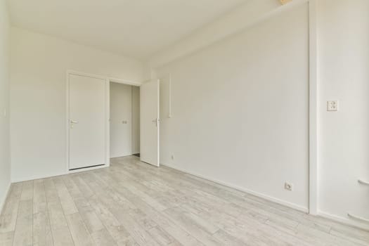 A spacious, minimalist interior showcasing an empty room with light-colored walls and wooden floors, ideal for showcasing modern design concepts.