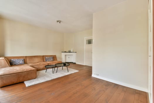 A spacious and stylish living room featuring a comfortable sofa, minimalist decor, and a warm wooden floor, perfect for relaxation and socializing.