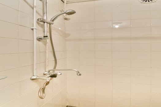 A clean and minimalistic shower area featuring white tiled walls, stainless steel fixtures, and a glass shelf, showcasing contemporary bathroom design.