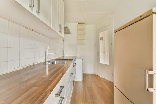A contemporary kitchen space featuring sleek white cabinetry, a wooden countertop, and minimalistic design elements. The room is well-lit and functional.