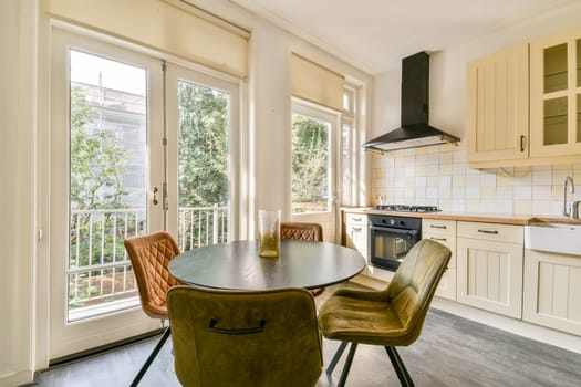 A bright and inviting modern kitchen featuring an elegant dining space. Natural light streams through large windows, enhancing the warm atmosphere of the room.