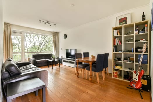 A spacious and inviting living room featuring modern furniture, large windows, and a warm wooden floor, showcasing an atmosphere of comfort and style.