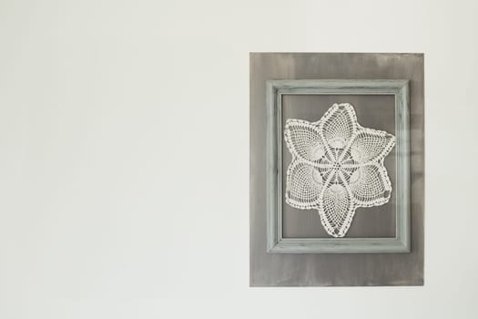 Crocheted napkins hang in a frame on the wall Village style