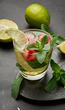Refreshing mojito cocktail with lime, mint, strawberry, and ice on dark background, close up