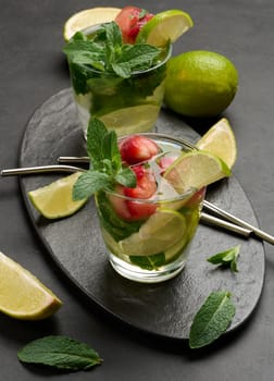 Refreshing mojito cocktail with lime, mint, strawberry, and ice on dark background