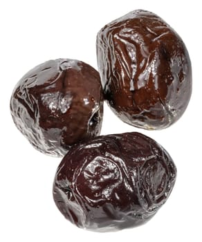 Three smooth, pitted black olives with a shiny, slightly wet surface are grouped together, isolated background