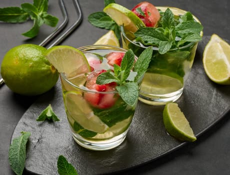 Refreshing mojito cocktail with lime, mint, strawberry, and ice on dark background, top view