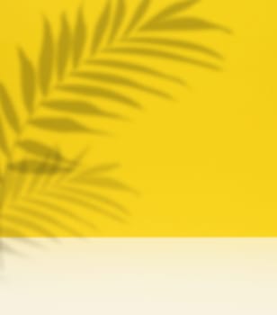 Soft, blurred shadows of palm leaves are cast across a solid light yellow background, creating a subtle and organic texture with copy space.