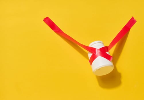 A small white bottle is tightly wrapped and secured with bright red electrical tape against a yellow background