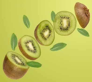 Sliced ​​ripe kiwi fruit and green mint leaves levitate on light green background