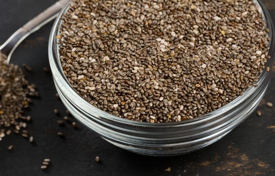 Clear glass bowl filled with dry chia seeds, close up