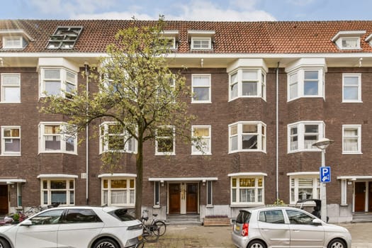 A contemporary urban residential building showcases modern architecture, complemented by trees and parked cars, alongside a peaceful street setting.