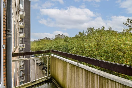 A contemporary balcony view showcasing a cityscape in the background along with vibrant green trees and a clear blue sky.