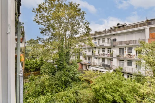 A scenic view from a balcony showcasing an urban apartment complex with lush greenery and trees nearby, creating a tranquil atmosphere in the city.