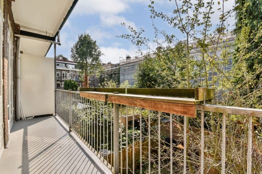 A tranquil balcony scene featuring a wooden railing and abundant greenery, ideal for relaxation and nature appreciation. Sunlight casts shadows on the floor.