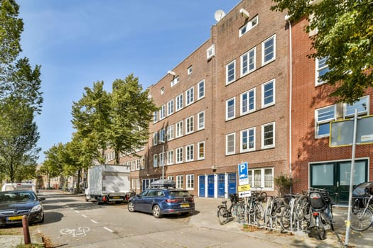 A picturesque street scene featuring vibrant trees, parked cars, and bicycles along a historic building in an urban setting.