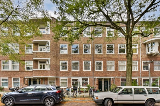 A picturesque view of an urban residential building, surrounded by lush greenery and parked cars, showcasing a blend of architecture and nature.