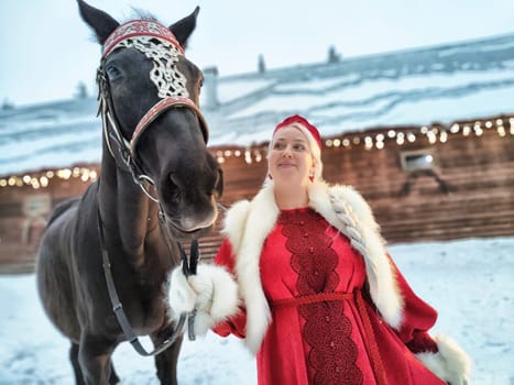 Girl in winter attire poses with a horse during Maslenitsa celebration, showcasing Russia's rich culture and beauty.