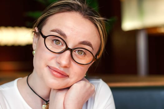 Portrait of a pretty girl in glasses looking at the camera. High quality photo