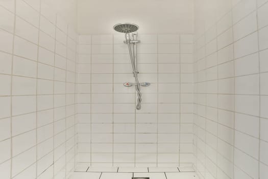 A sleek shower stall featuring white tiled walls and a contemporary showerhead. The minimalist design offers a clean and refreshing aesthetic.