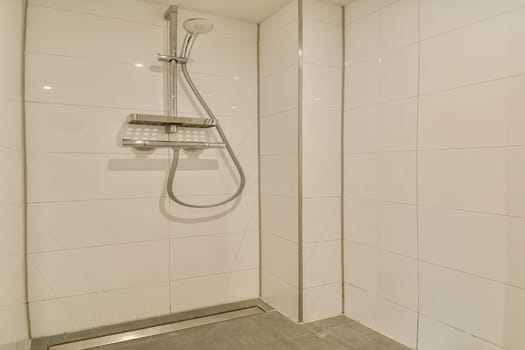 A sleek and minimalist shower stall featuring white tiled walls and a contemporary showerhead. The design emphasizes simplicity and cleanliness.