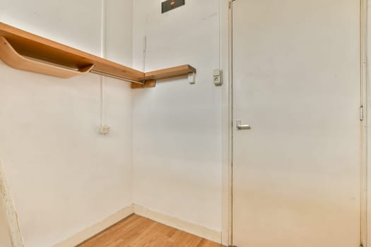 An interior view showcasing a simple, clean space with light wooden flooring and a plain white wall. Functional design emphasizes cleanliness and efficiency.