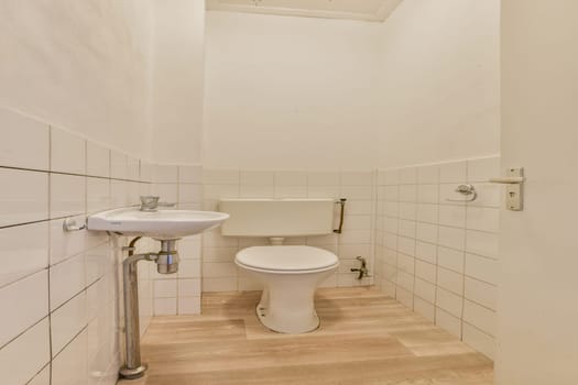 A clean and minimalistic bathroom showcasing white tiled walls, a simple toilet, and modern plumbing fixtures in a compact space.