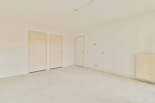A vacant room showcasing white walls, bare floor, and a simplistic design. The space is illuminated with natural light, emphasizing the minimal decor.