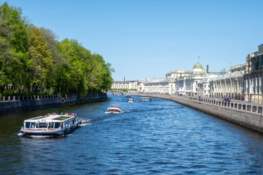 Saint-Petersburg, Russia - 05.21.24. River Fontanka scene with several boats cruising along a scenic waterway flanked by trees of Summer garden and historic architecture.