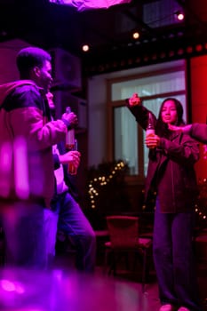 A group of friends celebrates a night out with drinks in hand while dancing and enjoying music in a colorful and lively venue, illuminated with enchanting lights.