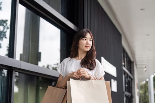A young woman happily carries shopping bags after a successful Black Friday shopping spree in a contemporary urban environment.