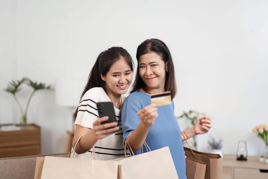 A happy mother and child smiling and holding paper bags after a successful shopping trip, standing in a cozy, modern home.