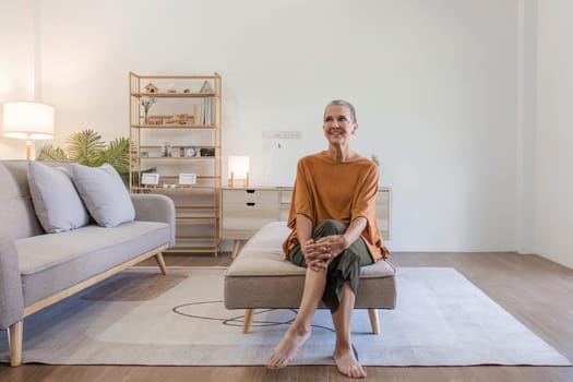 Elderly woman sitting comfortably in a modern living room, showcasing minimalist decor and natural lighting.